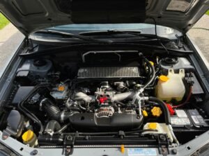 Close-up view of car engine with visible components under the open hood.