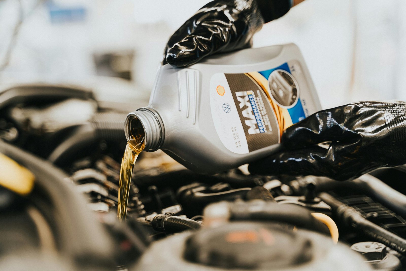 Close-up of a mechanic pouring engine oil into a car engine, highlighting maintenance work.