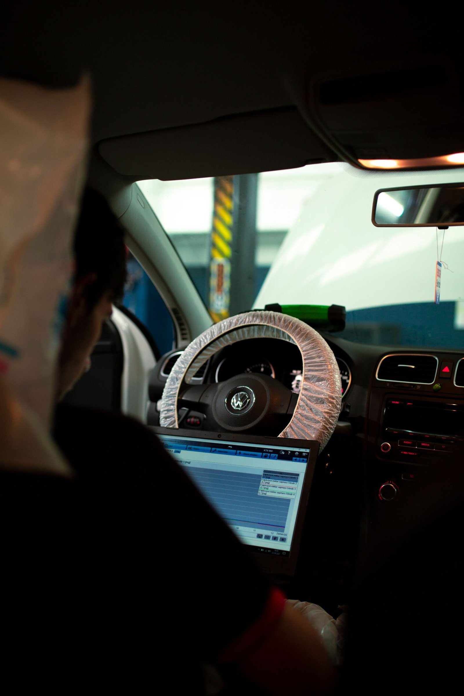electric-vehicle-service-in-dubai.Mechanic inside car using laptop for diagnostics. Ideal for automotive and technology themes.
