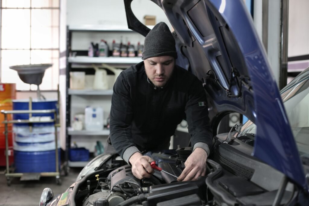 electric-vehicle-service-in-dubai.Man working under car hood in a garage, focused on engine repair